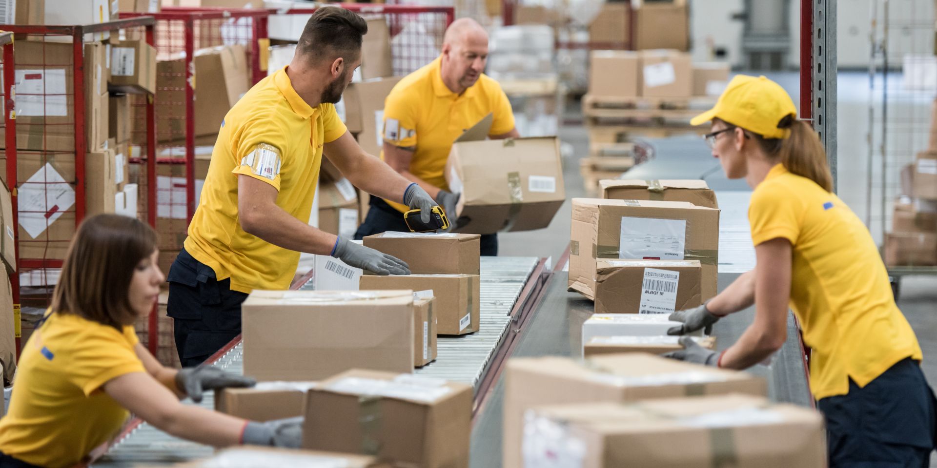 Four people sorting packages in a warehouse